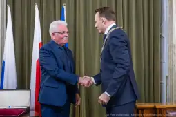 Dwaj mężczyźni uścisnęli sobie dłonie w formalnej atmosferze.