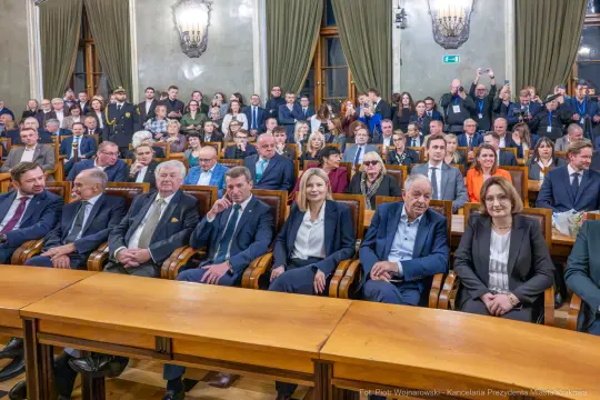 Spotkanie w sali obrad z udziałem wielu osób, w tym przedstawicieli władz.