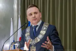 Mężczyzna w garniturze z łańcuchem prezydenckim przemawia podczas uroczystości.