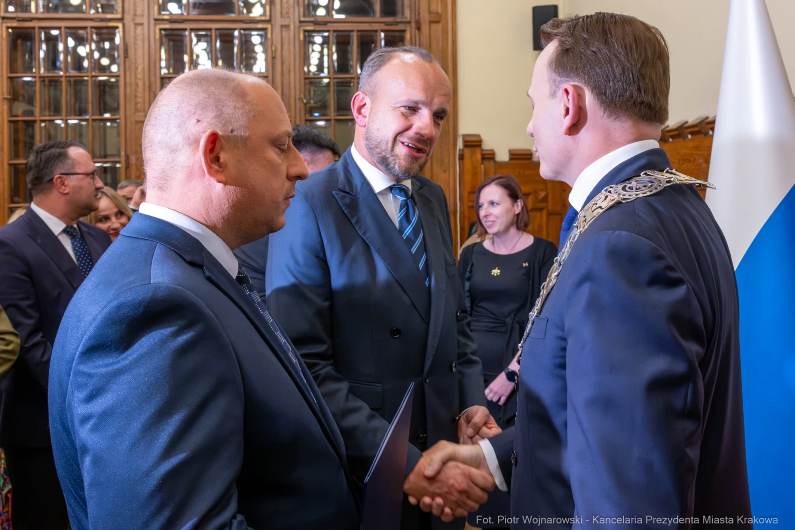 Uroczystość wręczenia odznaczeń, mężczyźni w garniturach, uściski dłoni.  Autor: Piotr Wojnarowski
