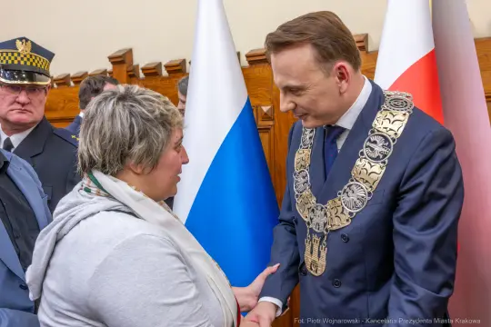 Spotkanie z przedstawicielem władz, rozmowa z kobietą, flagi Polski i Rosji w tle.