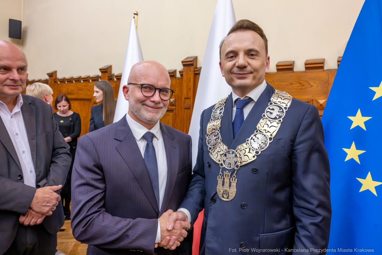 Dwóch mężczyzn w garniturach, jeden z łańcuchem prezydenckim, uściski dłoni, flagi w tle.  Autor: Piotr Wojnarowski