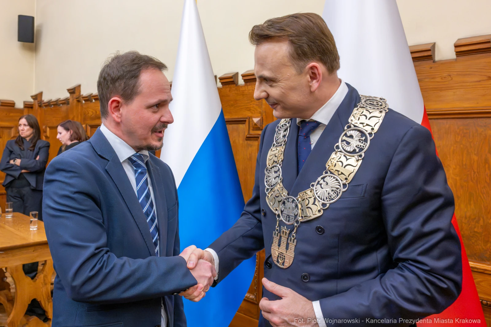 Dwaj mężczyźni w garniturach, jeden z łańcuchem prezydenckim, uściski dłoni. Flagi w tle.  Autor: Piotr Wojnarowski