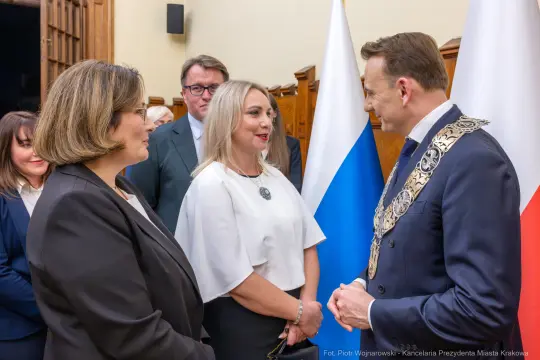 Spotkanie przedstawicieli władz z flagami Polski i Rosji w tle.