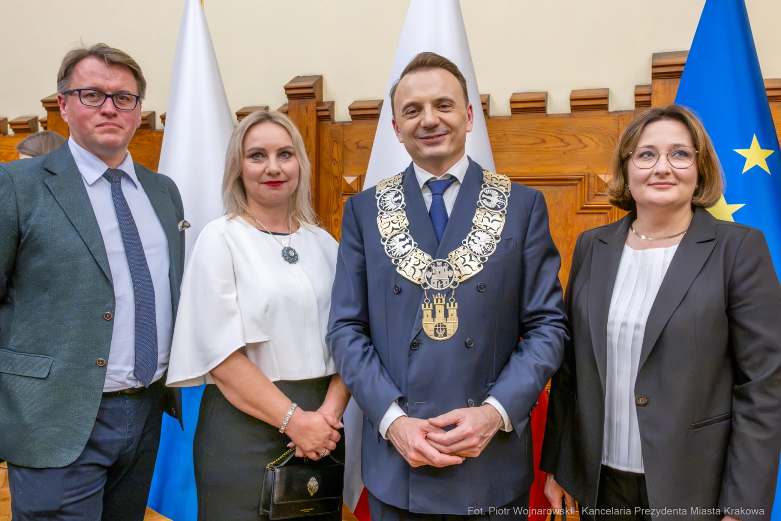 Cztery osoby w formalnych strojach, w tym mężczyzna z łańcuchem prezydenckim, w sali z flagami.  Autor: Piotr Wojnarowski