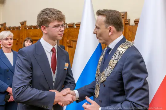 Młody mężczyzna uścisnął dłoń prezydenta Krakowa w oficjalnej atmosferze.