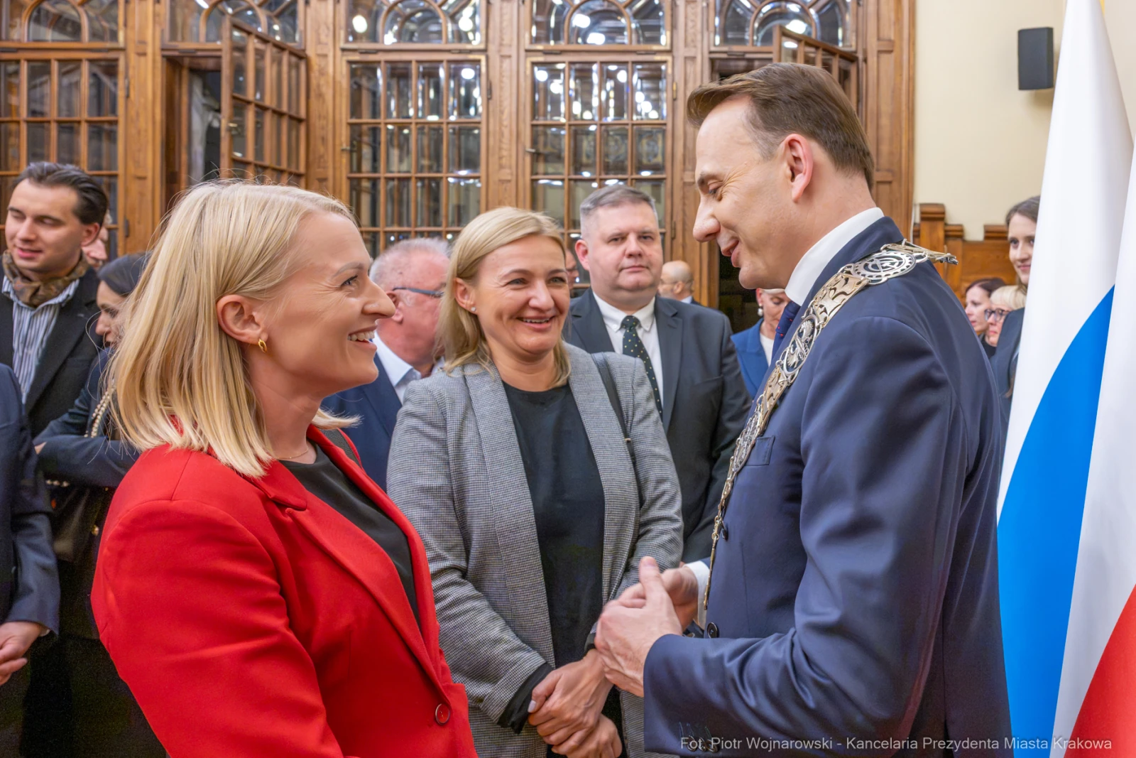 Spotkanie dwóch kobiet i mężczyzny w formalnym otoczeniu, z flagą w tle.  Autor: Piotr Wojnarowski