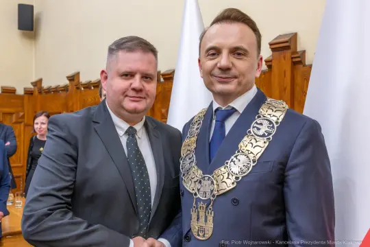 Dwóch mężczyzn w garniturach, jeden z łańcuchem prezydenckim, uściski dłoni.
