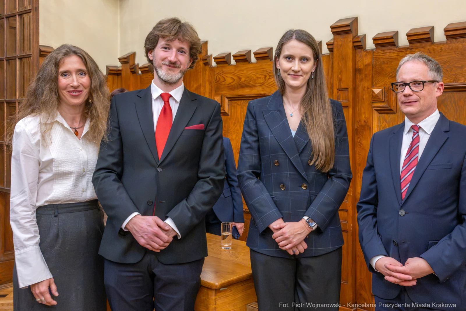 Cztery osoby w formalnych strojach, stojące w drewnianym wnętrzu.  Autor: Piotr Wojnarowski