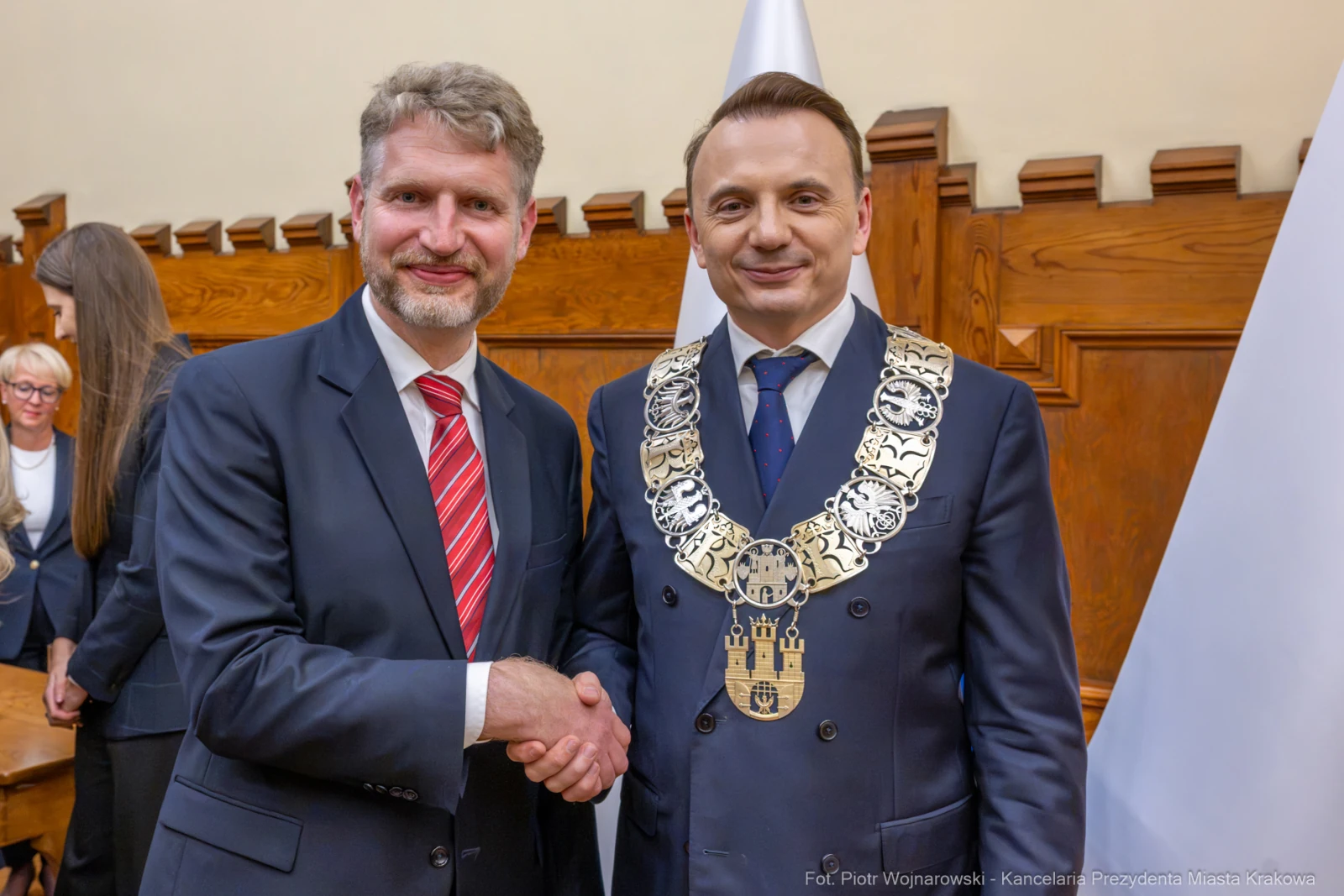 Dwaj mężczyźni w garniturach uścisnęli sobie dłonie, jeden z nich ma łańcuch prezydencki.  Autor: Piotr Wojnarowski