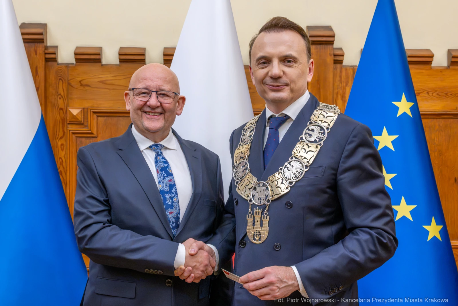 Dwóch mężczyzn uścisnęło sobie dłonie, jeden z nich w łańcuchu prezydenckim. Flagi w tle.  Autor: Piotr Wojnarowski