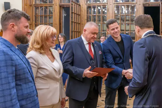 Uroczystość wręczenia nagród w eleganckiej sali z uczestnikami w formalnych strojach.