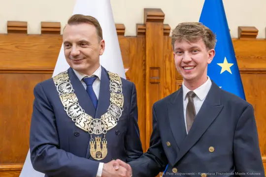 Burmistrz Krakowa wręcza medal młodemu laureatowi w uroczystej atmosferze.