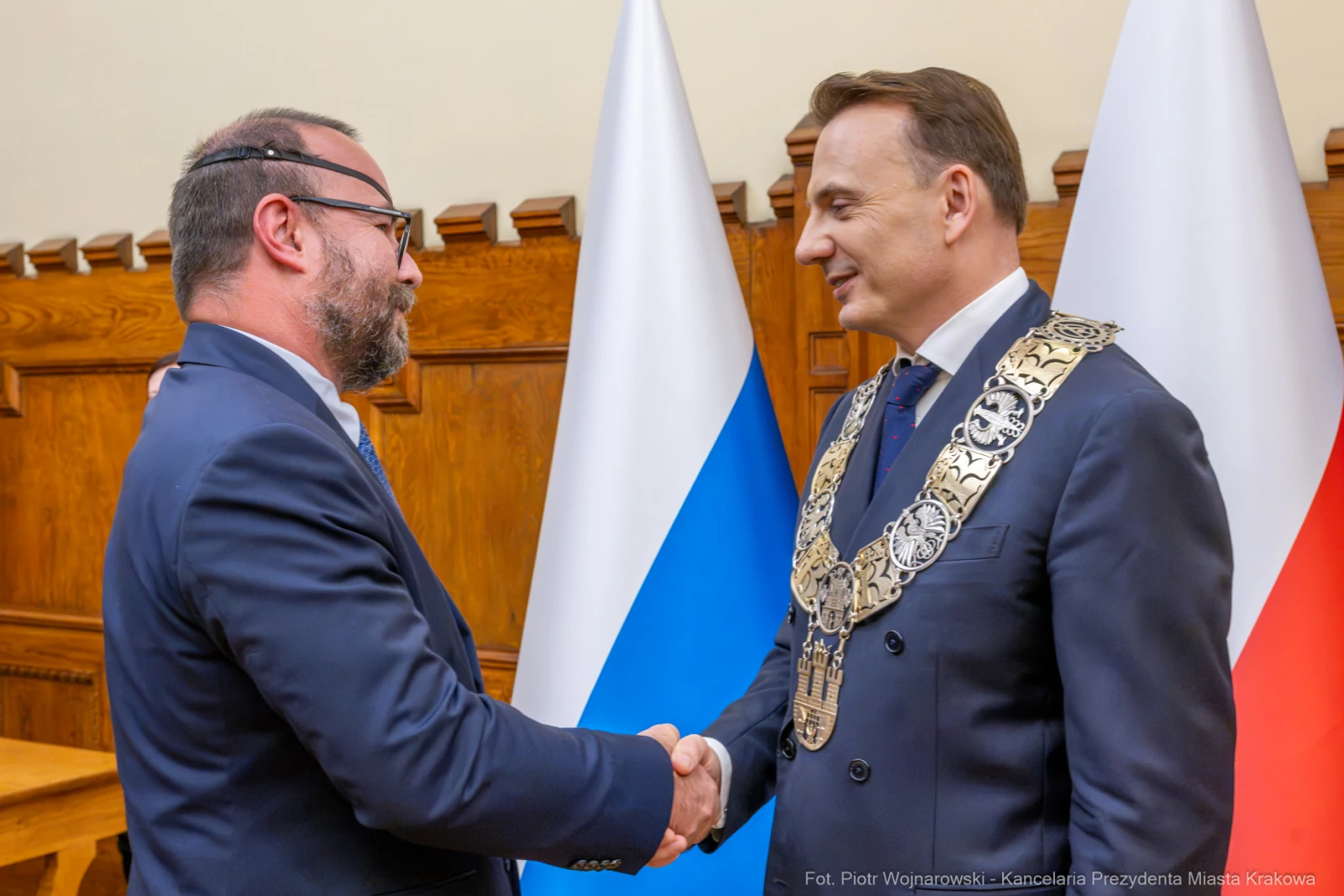 Dwaj mężczyźni uścisnęli sobie dłonie, w tle flagi Polski i Rosji.  Autor: Piotr Wojnarowski