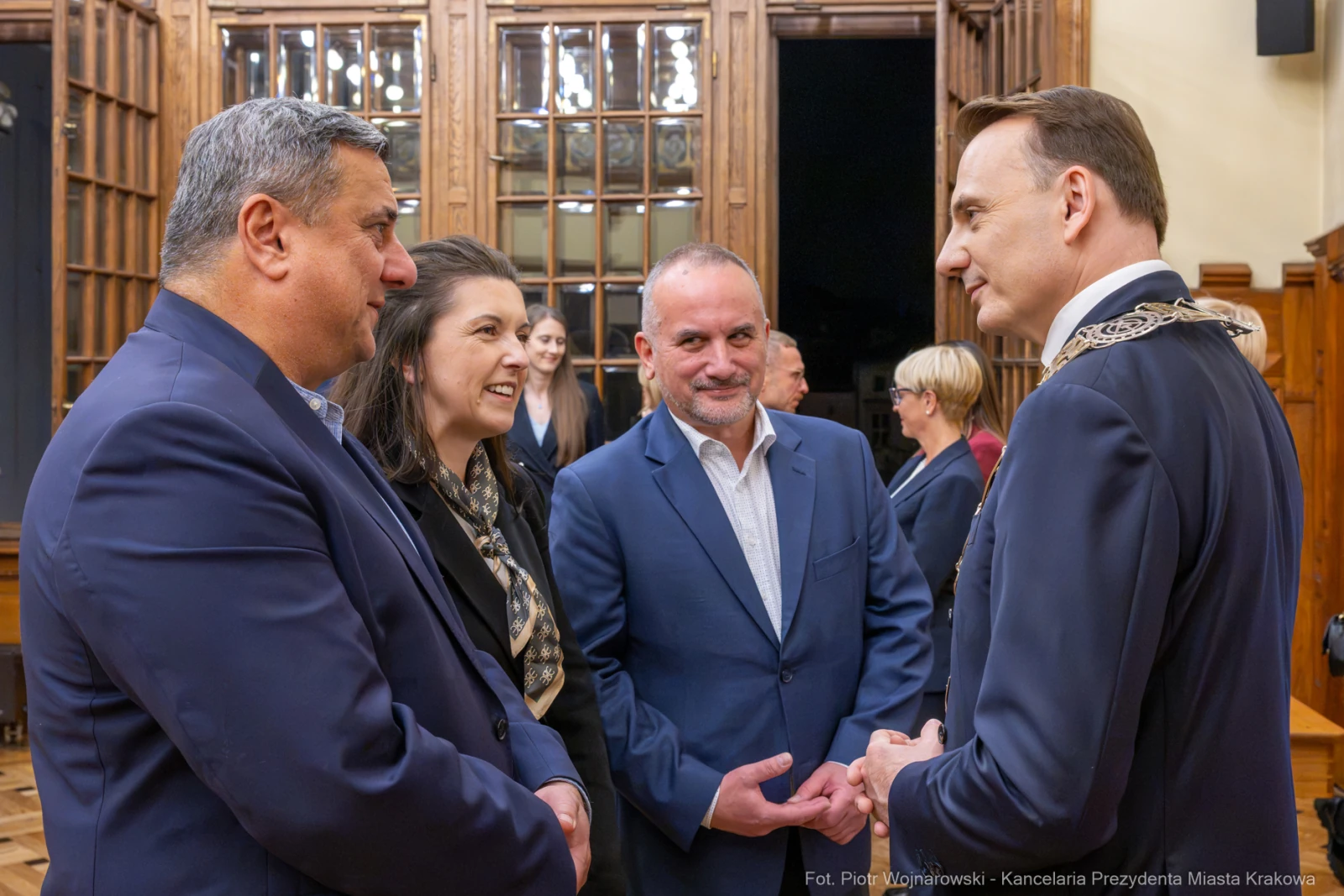 Cztery osoby rozmawiają w eleganckim wnętrzu, w tle widoczne drewniane elementy.  Autor: Piotr Wojnarowski