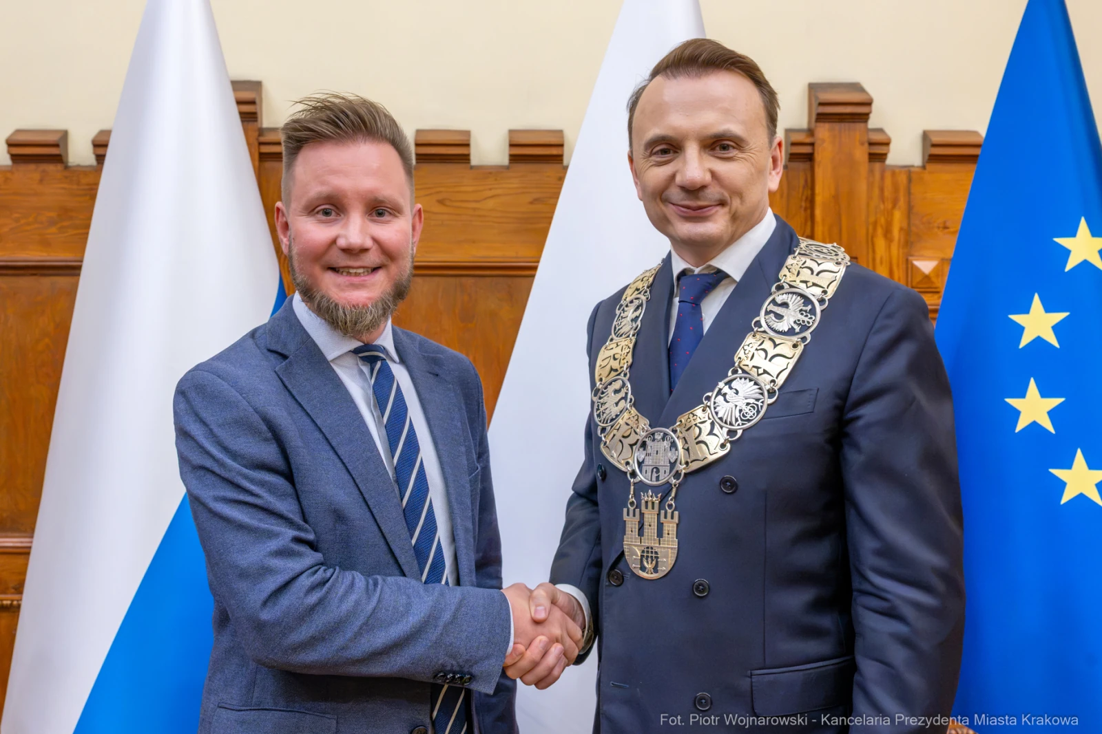 Dwaj mężczyźni w garniturach, jeden z łańcuchem prezydenckim, uściski dłoni, flagi w tle.  Autor: Piotr Wojnarowski