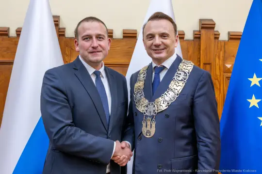 Dwóch mężczyzn w garniturach uścisnęło sobie dłonie, jeden z nich ma łańcuch prezydencki.
