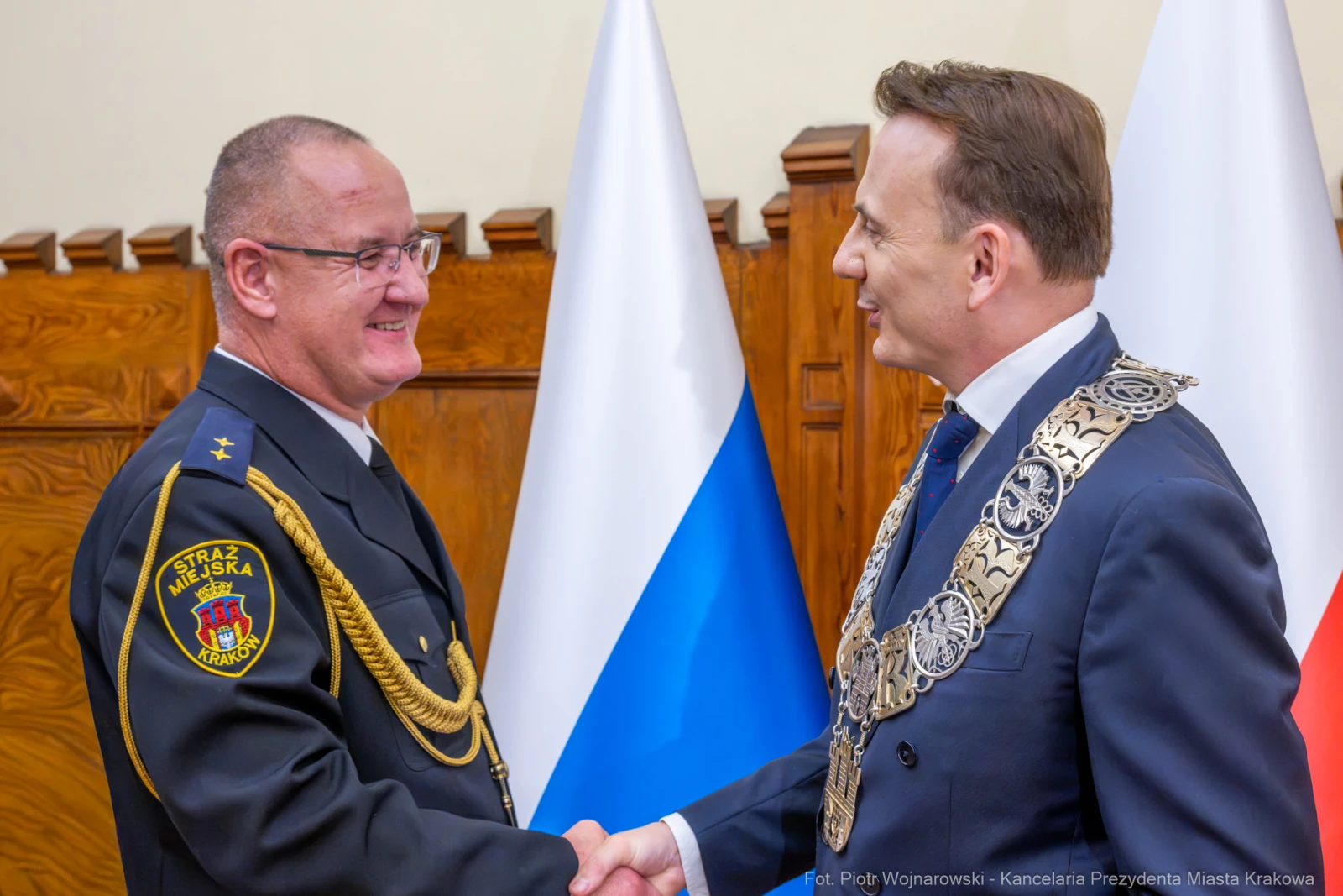 Spotkanie dwóch mężczyzn w mundurze i garniturze, uściski dłoni, flagi w tle.  Autor: Piotr Wojnarowski