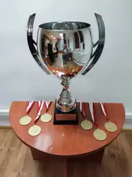 Puchar i medale sportowe na drewnianym stole.