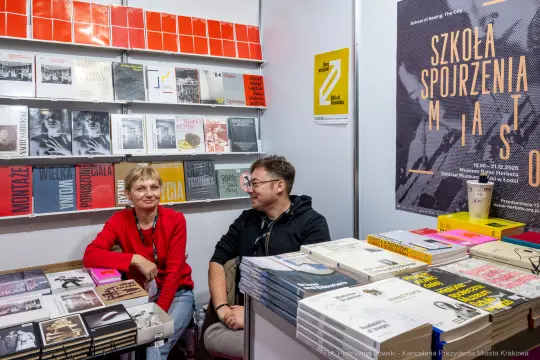Dwoje ludzi siedzących przy stoisku z książkami na targach.