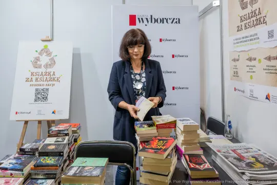 Kobieta przegląda książki na stoisku z literaturą.