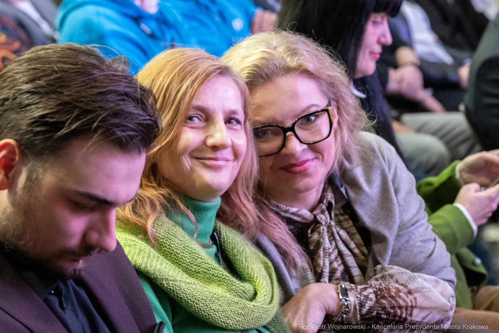 Grupa osób siedzących razem, uśmiechające się kobiety i mężczyzna z telefonem.  Autor: Piotr Wojnarowski