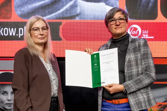 Dwie kobiety trzymające dyplom wyróżnienia.