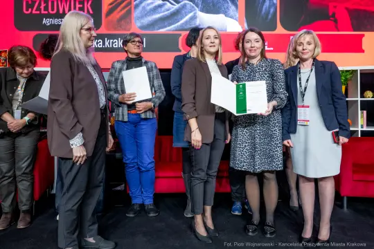 Wręczenie nagród w trakcie wydarzenia, uczestnicy z dyplomami i uśmiechami.