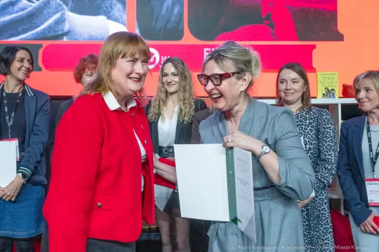 Uśmiechnięte kobiety odbierają nagrody podczas uroczystości wręczenia wyróżnień.