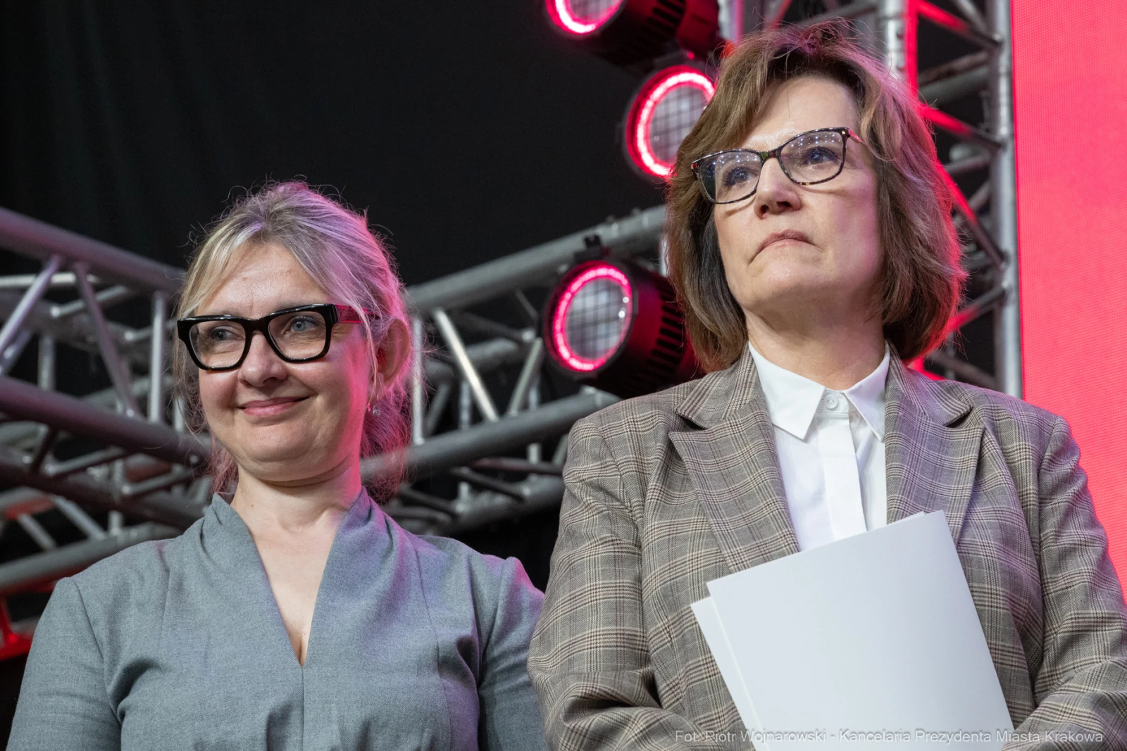 Dwie kobiety w okularach, stojące na tle sceny z oświetleniem.  Autor: Piotr Wojnarowski