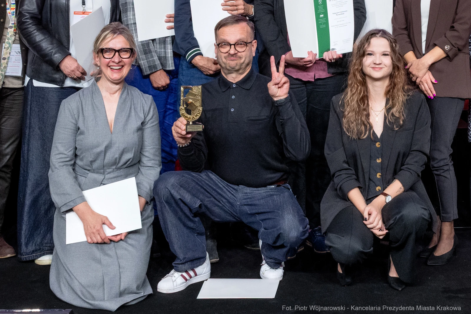 Uczestnicy ceremonii wręczenia nagród, mężczyzna z trofeum w dłoni, uśmiechnięte kobiety obok.  Autor: Piotr Wojnarowski