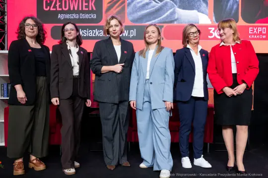 Grupa kobiet w eleganckich strojach na wydarzeniu promującym książki.