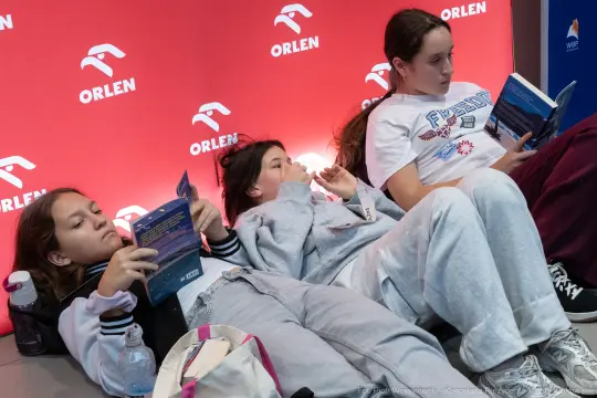 Trzy dziewczyny leżą na podłodze, czytając książki w strefie relaksu.