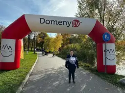 Brama startowa z napisem Domeny.tv w parku, obok ścieżki spacerowej.