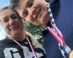 Dwie kobiety z medalami na szyi, uśmiechające się do kamery.