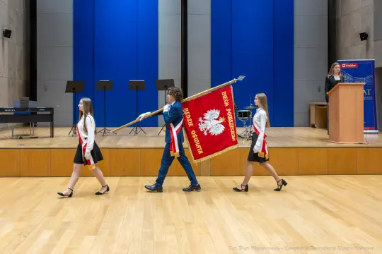 Uczniowie niosą sztandar podczas uroczystości szkolnej.