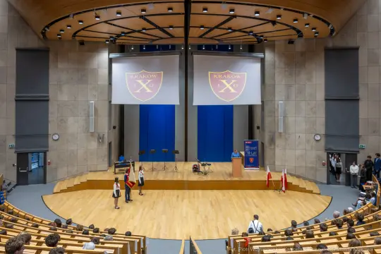 Aula z podium, flagami i ekranami, przygotowana na wydarzenie w Krakowie.
