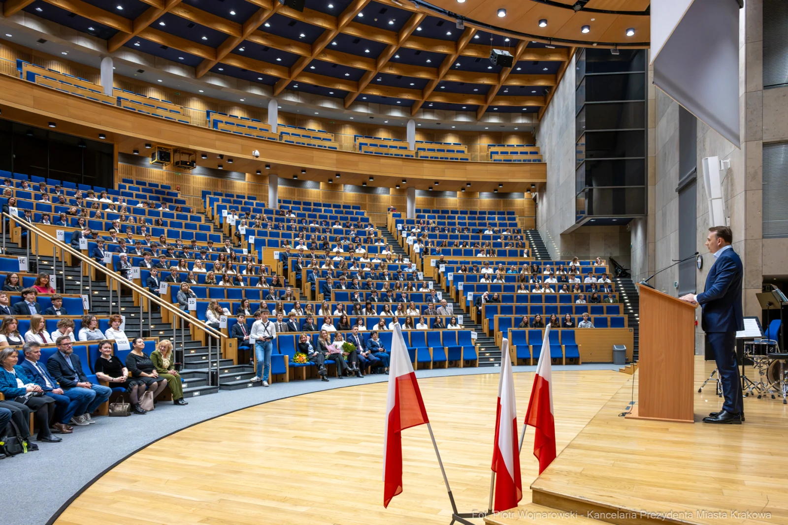 Wystąpienie mężczyzny na scenie przed dużą publicznością w nowoczesnej sali.  Autor: Piotr Wojnarowski