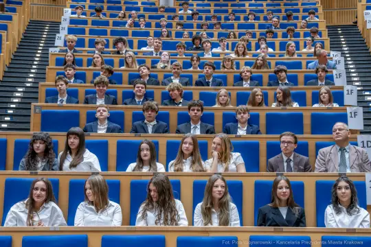 Grupa uczniów siedzących w sali wykładowej.