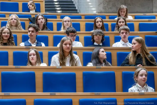Grupa młodych ludzi siedzących na widowni w sali obrad.
