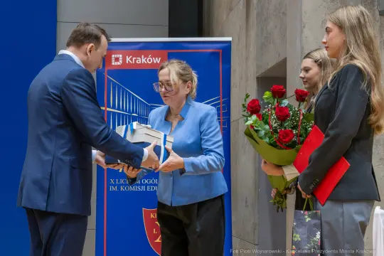 Wręczenie nagród w Krakowie, obecność osób z kwiatami i dyplomami.