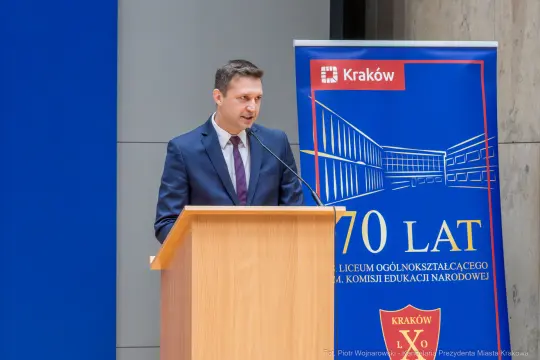 Mężczyzna w garniturze przemawia przy podium z logo Krakowa i napisem 70 lat.