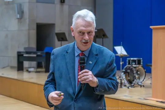 Mężczyzna w garniturze przemawia do publiczności w sali wykładowej.