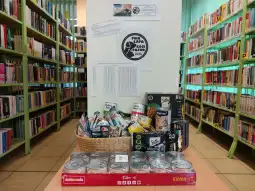 Kosz z jedzeniem i artykułami dla zwierząt w bibliotece, otoczony regałami z książkami.