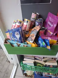 Pudełko z karmą dla zwierząt oraz przekąskami, obok książki.