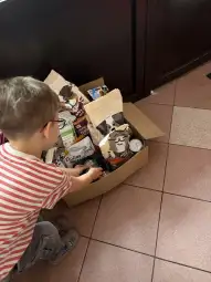 Chłopiec wyciąga produkty z kartonu z jedzeniem dla zwierząt.