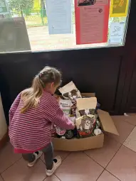 Dziewczynka przegląda paczki z jedzeniem dla zwierząt w kartonie.