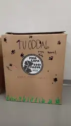 Karton z napisem o zbiórce dla psów, z rysunkami łap i hasłem o wspólnej pomocy.