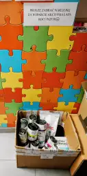 Pudełko z karmą dla zwierząt obok kolorowej ściany z puzzlami.
