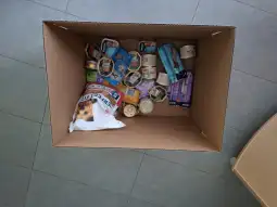 Pudełko z jedzeniem dla psów, w tym puszki i saszetki.